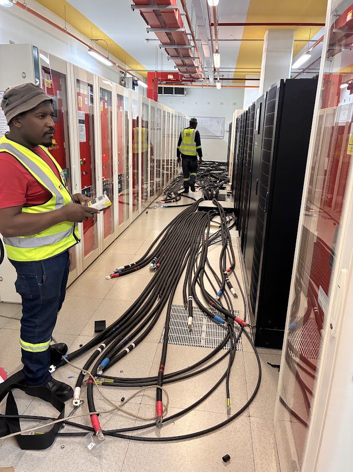 Technician pulling LV cable in a live data hall
