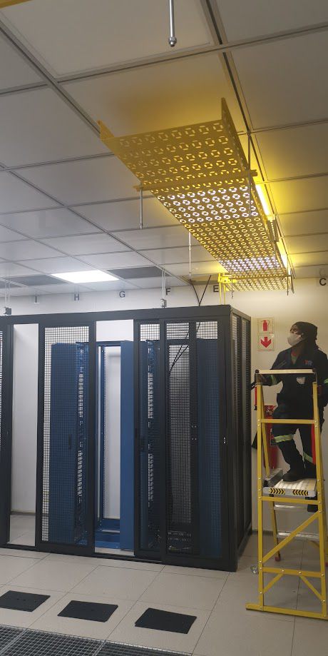 Technician installing cable containment above server racks